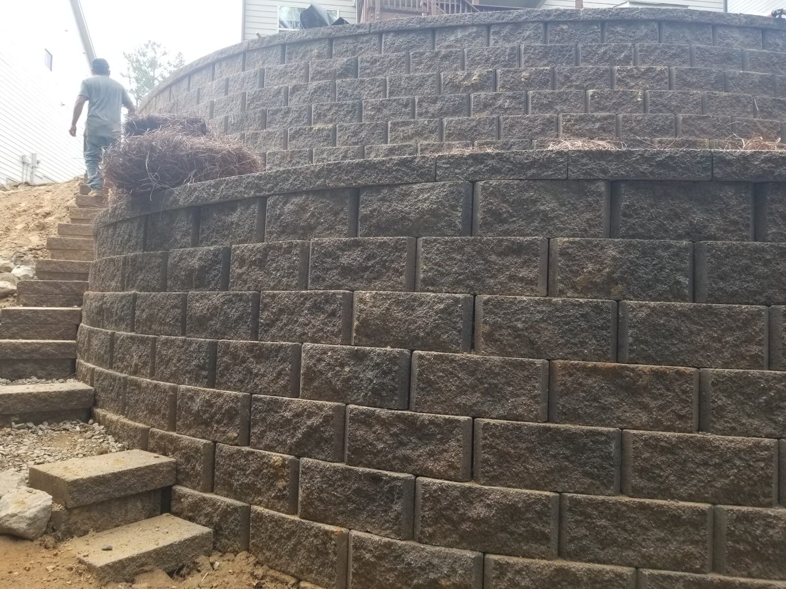 Multi-tier curved block terrace wall retaining a steep grade behind a structure