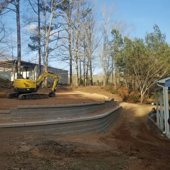 Curved retaining wall under construction with excavator and crew