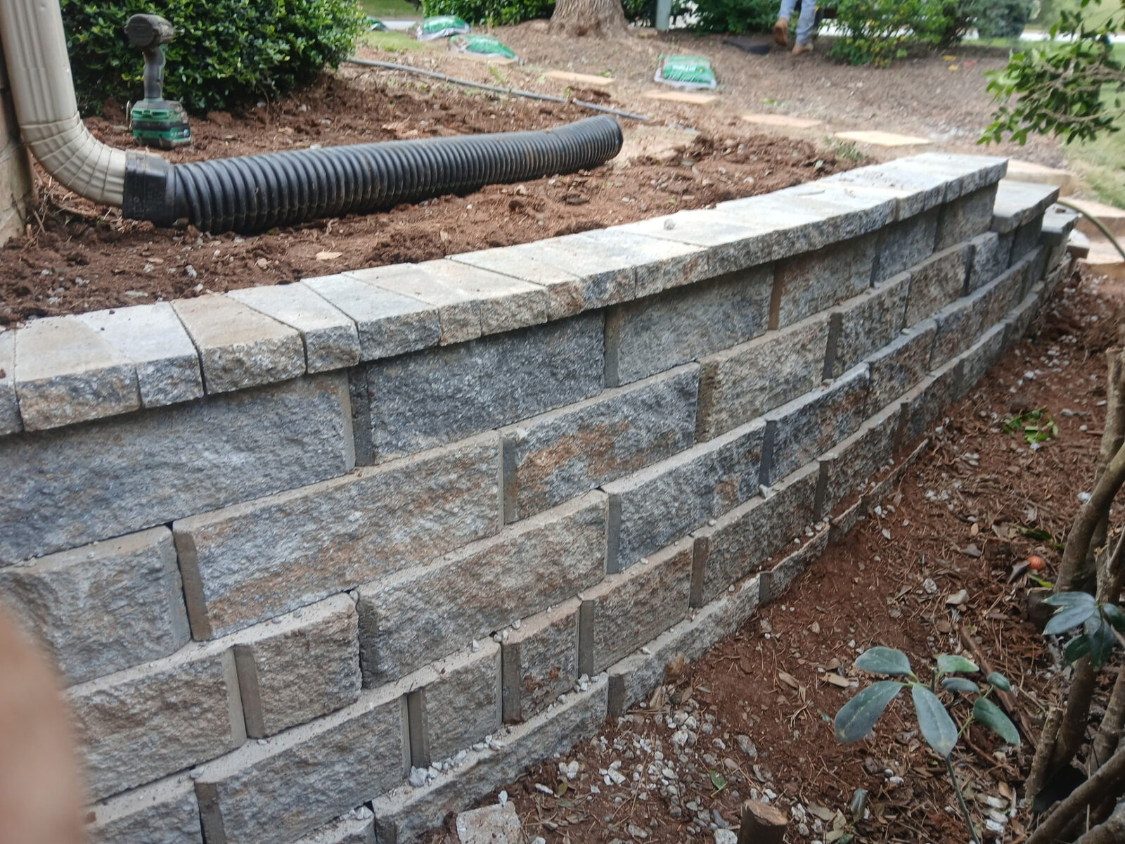 Finished granite-tone block wall with capstones curving along a property line