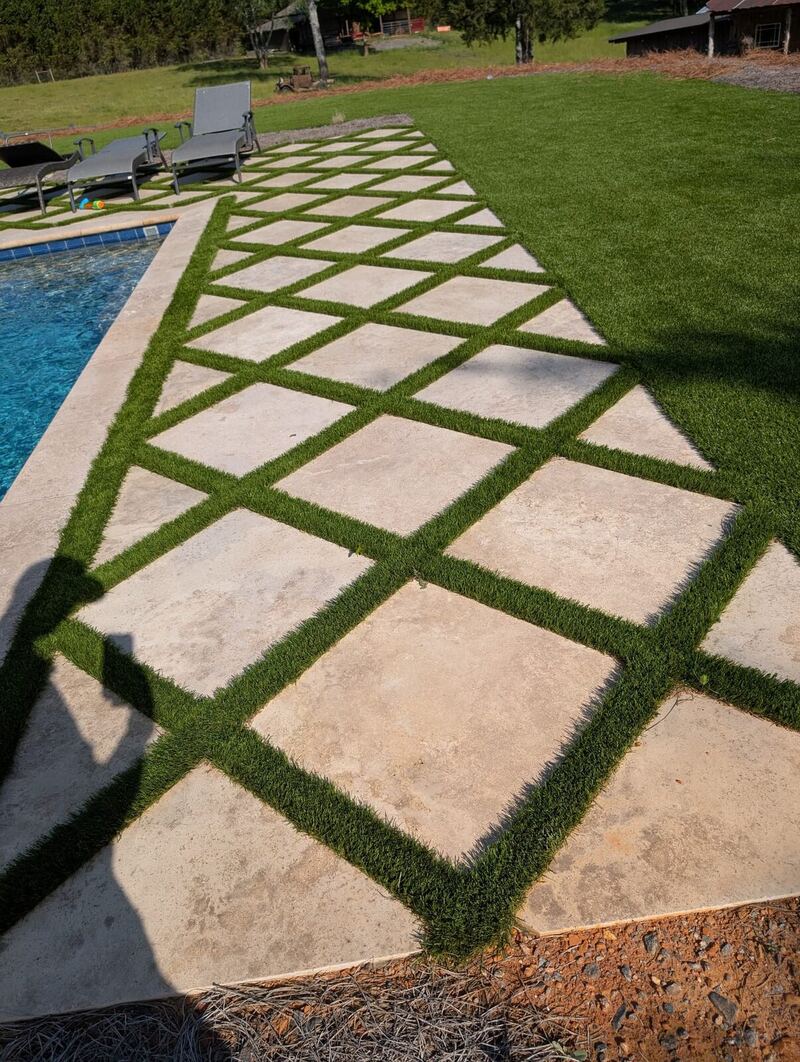 Diamond-pattern pavers with turf inlay beside a pool, installed by The Wall Guy