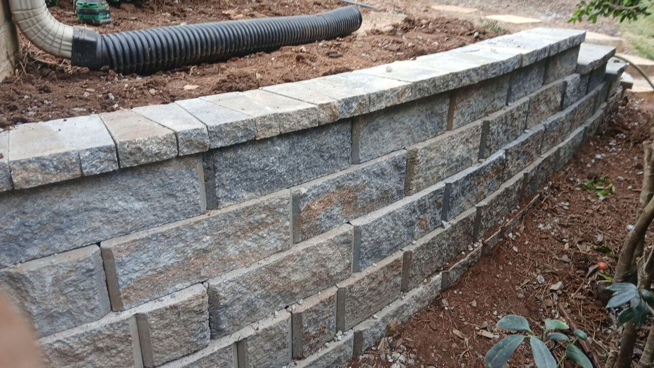 Curved granite block retaining wall with capstones built by The Wall Guy in Georgia