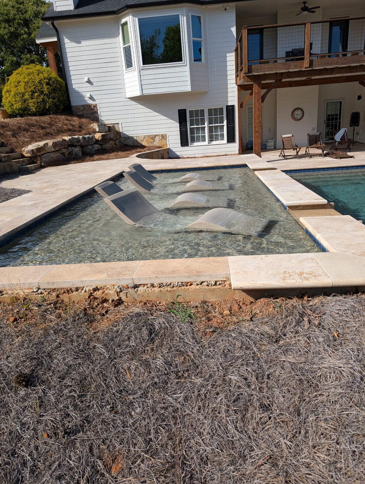Travertine pool coping and deck with in-pool loungers built by The Wall Guy